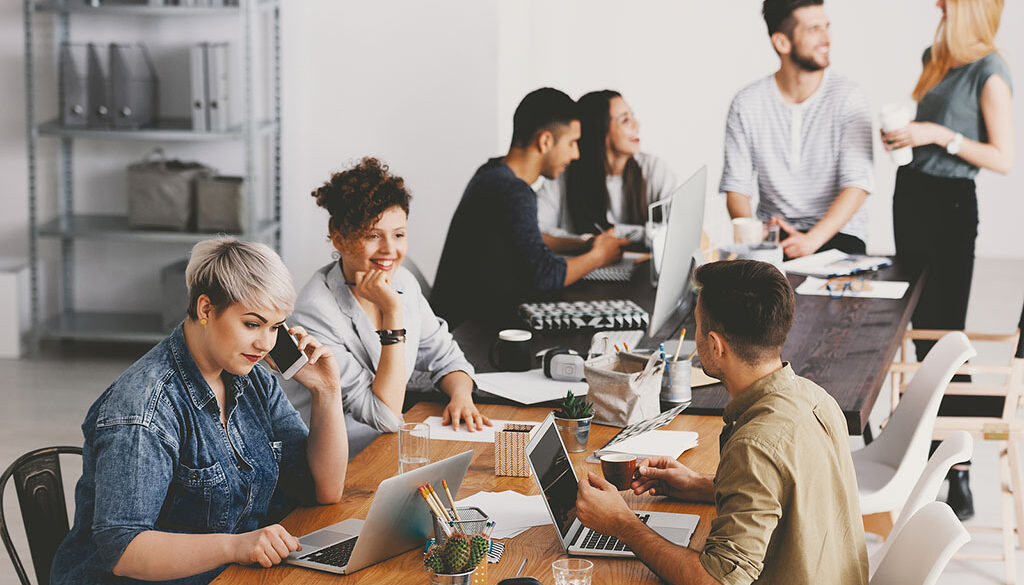 A Group of Coworkers Sitting at Two Separate Tables Collaborating With Each Other Digital Marketing Agency