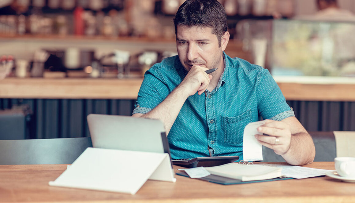 Closeup Of A Business Owner Sitting At A Table Checking Over His Business Expenses On A Tablet What Is Account Reconciliation