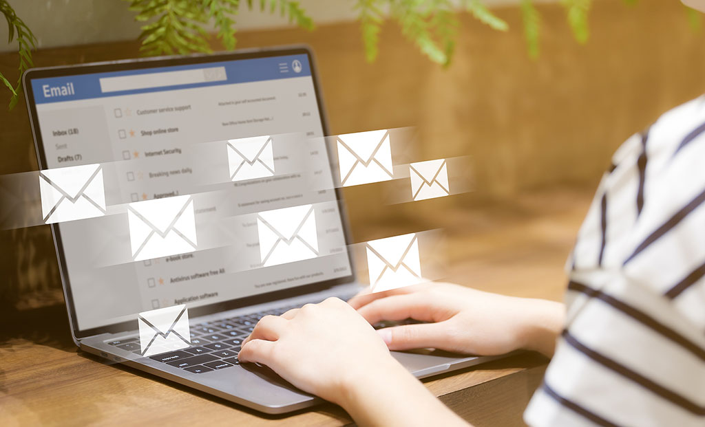 Closeup of a Woman Looking At Her Email Inbox With Email Icons Flying From Her Laptop Screen Why Is Email Marketing Effective
