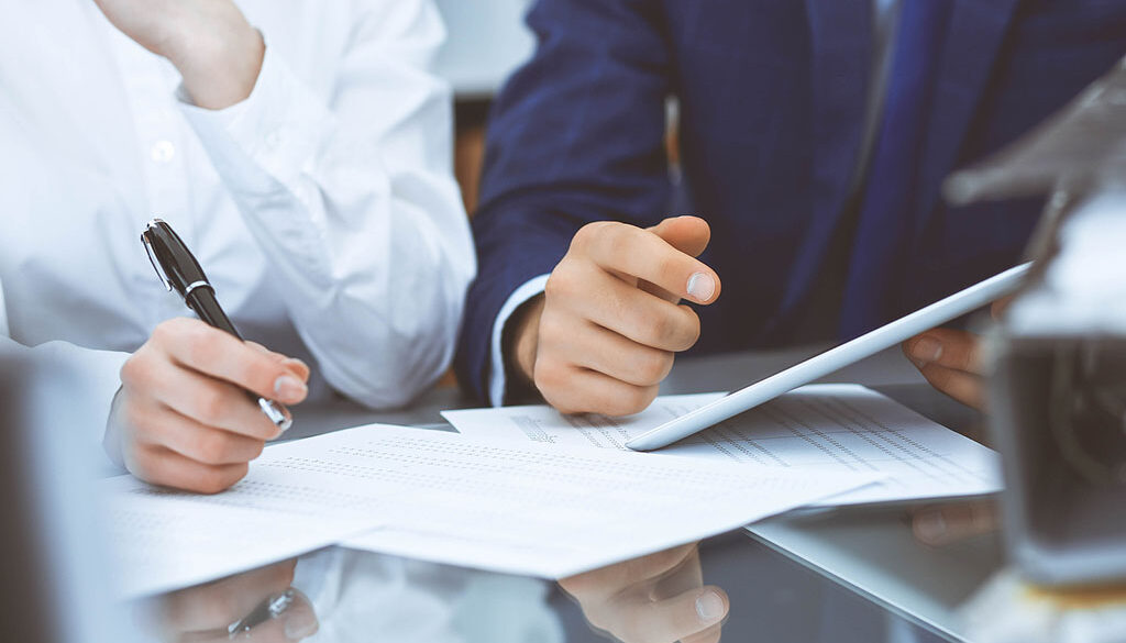 Closeup Of Two Bookkeepers Reviewing Financial Documents In-House Vs Outsourced Bookkeeping