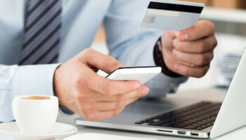 Closeup Of A Businessman Holding A Cell Phone And Credit Card In Front Of A Laptop Business Fraud Prevention