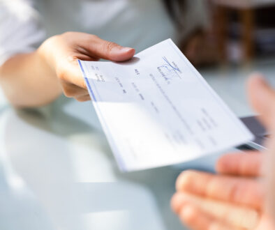Closeup Of A Woman Handing A Paycheck To Her Employee Types Of Pay Periods
